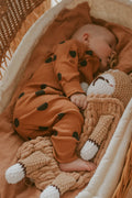 Baby sleeps in the crib with beige color bear toy 