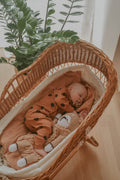 Baby laying in the crib with beige color bear toy 